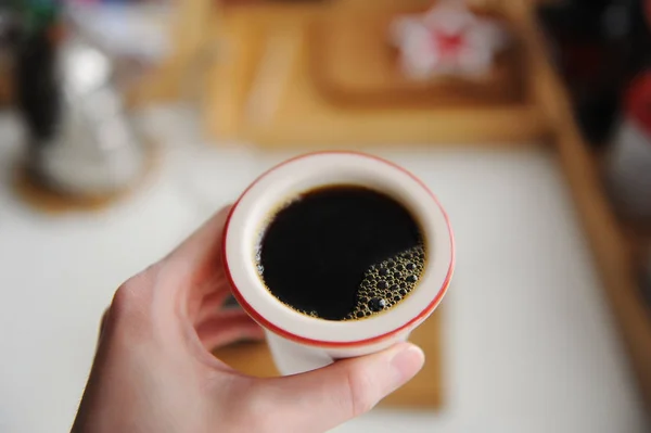 Café filtre noir frais dans une tasse en céramique sans poignée à la main. Vue de dessus, gros plan — Photo