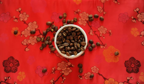 China concepto de café de especialidad. Frijol asado en taza blanca sobre tela de patrón rojo tradicional chino. Vista superior — Foto de Stock