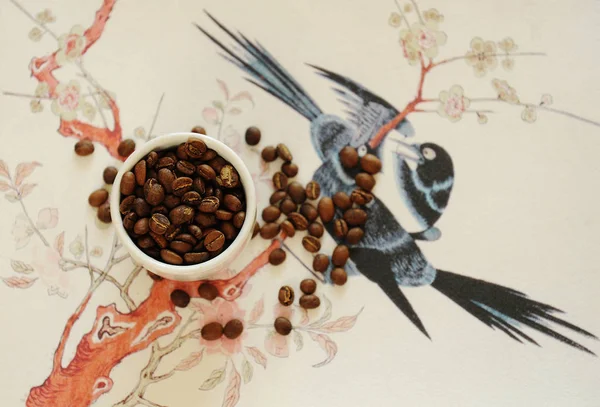 China concepto de café de especialidad. Frijol asado en taza blanca y sobre fondo tradicional chino. Vista superior — Foto de Stock