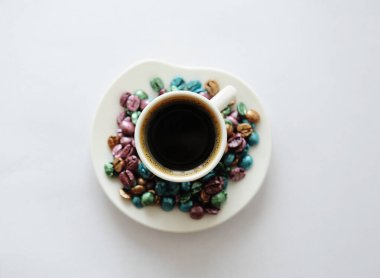 Bir fincan kahve. Etrafa saçılmış çok renkli inci kahve çekirdekleri. Paskalya fikri. Beyaz arkaplan izole.