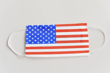 ABD bayrağı taşıyan koruyucu tıbbi maske. Devlet sınırlarının kapatılması ve pandemik denetimin kavramsal sembolü