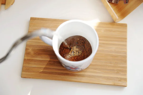 Preparando café en taza. Verter agua de la tetera de cuello de cisne en la taza con vista superior café recién molido — Foto de Stock