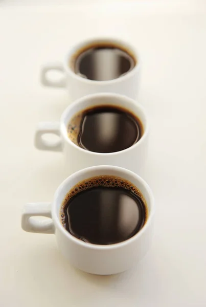 Drei Weiße Tassen Mit Schwarzem Kaffee Nacheinander Auf Weißem Hintergrund — Stockfoto