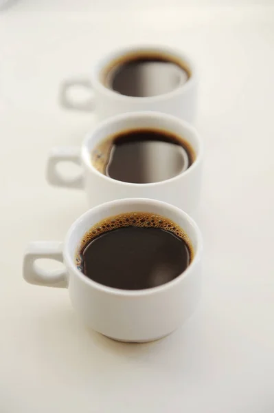 Τρία Λευκά Φλιτζάνια Μαύρο Καφέ Ένα Μετά Άλλο Λευκό Φόντο — Φωτογραφία Αρχείου