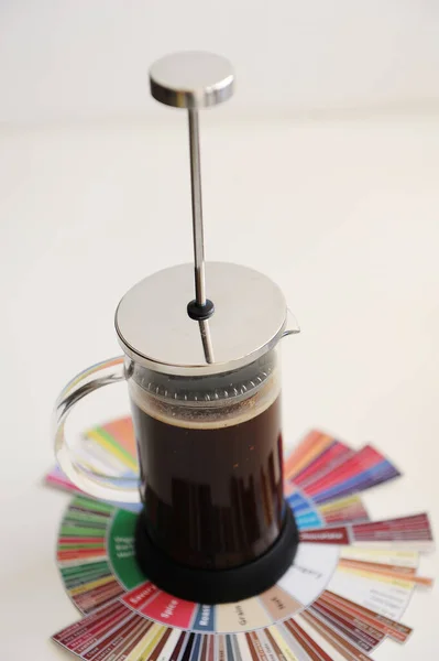 French press with ground coffee. On coffee Taster\'s Flavor Wheel. Plunger not lowered. White background. Specialty coffee concept