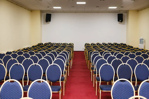Leerer Konferenzsaal mit blauen Stühlen und rotem Teppich — Stockfoto
