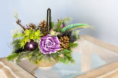 Noel ağaç dalları ve yapay çiçek buketi vardır. 