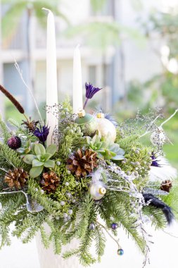 Noel ağaç dalları ve yapay çiçek buketi vardır. 