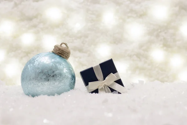 Caja de regalo y bola de vidrio están en la nieve . Fotos De Stock Sin Royalties Gratis