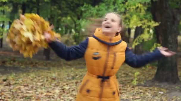 Junges Mädchen mit einem Strauß spinnender Blätter im Park. — Stockvideo