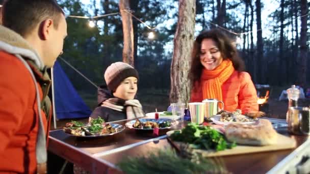 Ευτυχισμένος νεαρή οικογένεια κάθεται στο τραπέζι και ομιλίας, φθινόπωρο δάσος. — Αρχείο Βίντεο