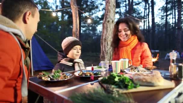 Felice giovane famiglia seduta a tavola e parlare, foresta autunnale . — Video Stock