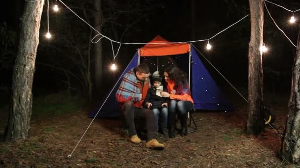 Joven familia feliz hace selfie en el bosque en el fondo de la tienda de campaña . — Vídeo de stock