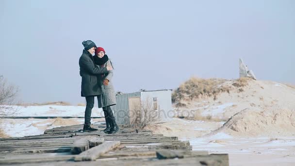 Mladý kluk a dívka v zimě одеваю, objetí a užít si scenérie zimní. — Stock video