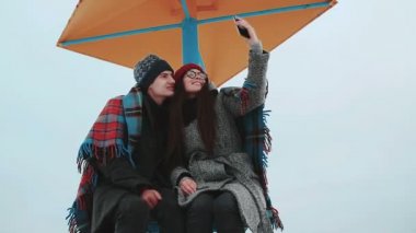 Bir battaniye ile örtülü iki çekici insan selfie karşı gri gökyüzü olun..