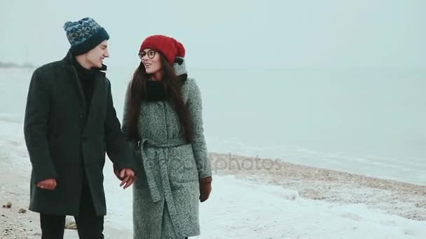 Щаслива пара, в теплому одязі, виходити на берег моря, позаду сірого неба — стокове відео
