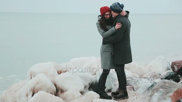 Ijzige stenen ridge. Jong (echt) paar staande op de oever van de zee van de winter. vergrote weergave. — Stockvideo