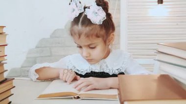 Masada oturan bir çocuk parmak sayfa kitap kitap ön plan yığını arasında yol açar.