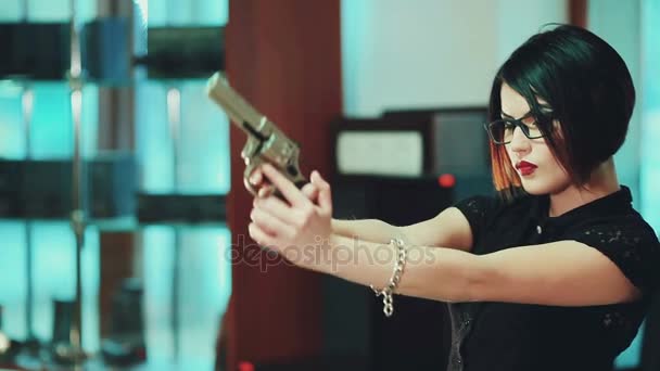Μελαχρινή κοπέλα με τα γυαλιά με μαύρο σκελετό, στοχεύουν σε ένα στόχο, κρατώντας ένα όπλο. — Αρχείο Βίντεο
