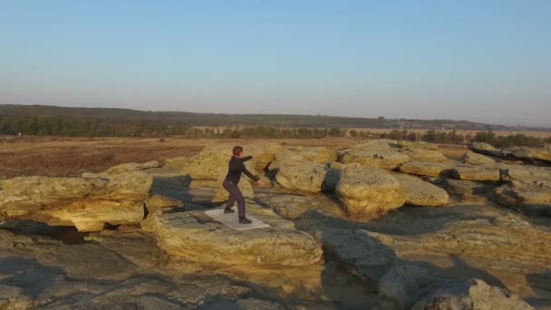 Un uomo impegnato nella ginnastica cinese, sulle rocce al tramonto. Aerea . — Video Stock