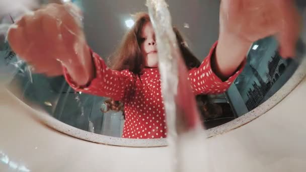 Молодая девушка умывается в ванной и смотрит в зеркало. Видео с медленным движением — стоковое видео