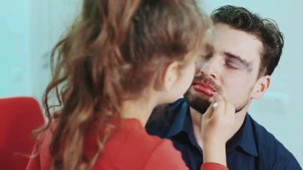 Una famiglia divertente. Padre e sua figlia bambina dipingono labbra e occhi a suo padre. Vista da vicino . — Video Stock