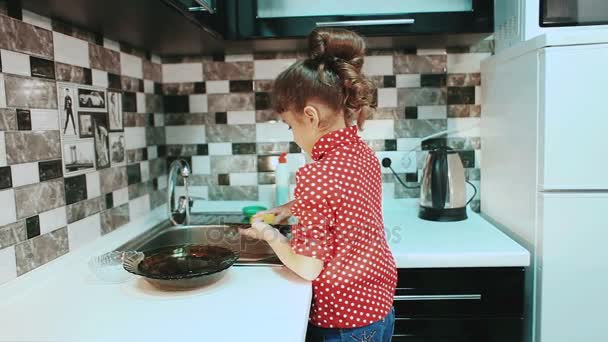 Маленькая девочка моет посуду на кухне . — стоковое видео