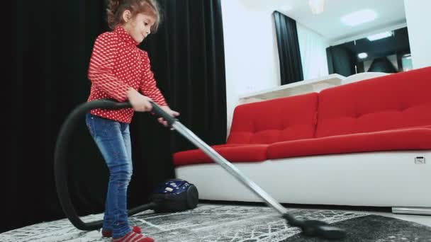 Kleines Mädchen putzt mit Staubsauger, grauer Teppich. — Stockvideo