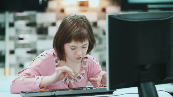 Chica con síndrome de Down sentada en una computadora en casa y escribiendo texto . — Vídeos de Stock