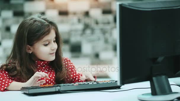 Malá školačka s tmavými vlasy a halenku s puntíky, práce doma počítač, psaní textu. — Stock video