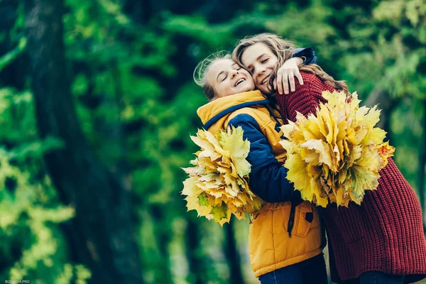 Yaprakları parkta bir grup ile iki kız kardeş kucaklaşması.