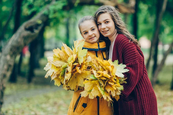 Yaprakları parkta bir grup ile iki kız kardeş kucaklaşması.