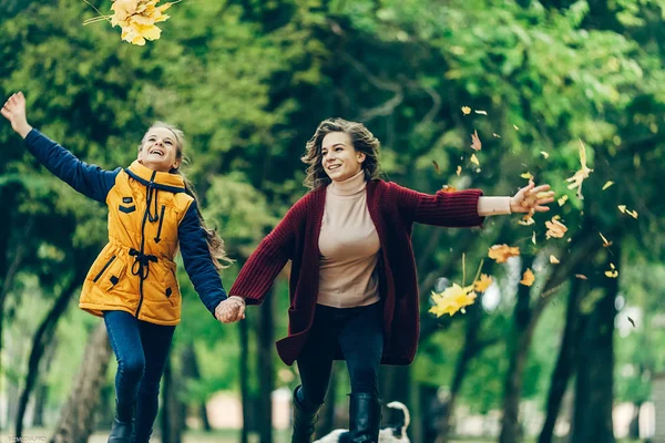 İki kız kardeş sonbahar parkta yürürken elele.