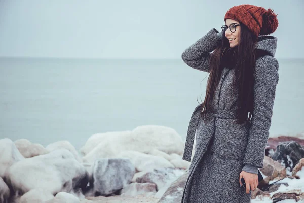 Genç kız kış denizinde mesafe içine buz gibi bakışları bir arka plan üzerinde taşlar.