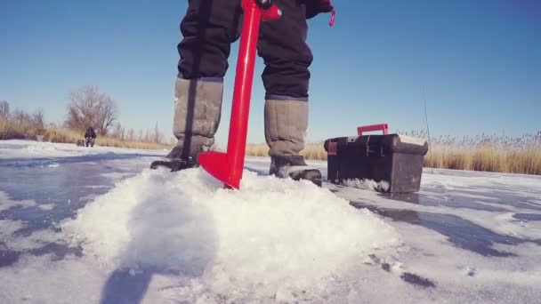 Taladro de hielo pasa por el hielo frío y hacer un agujero para la pesca de hielo. pesca con hielo . — Vídeo de stock