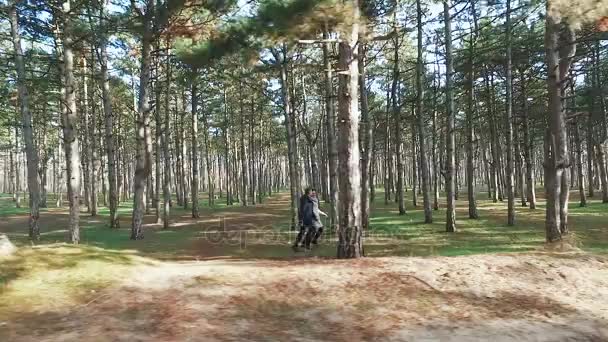 Девушка с парнем бежит среди сосен в лесу . — стоковое видео