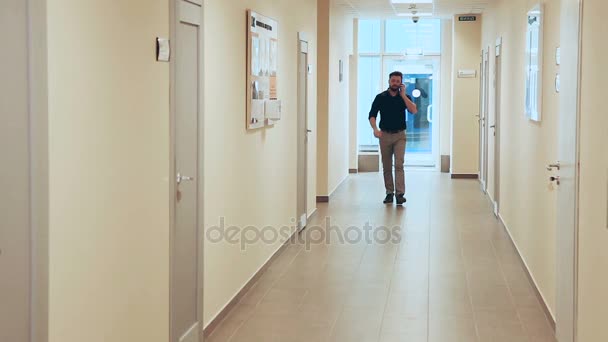 Hombre caminando a través de un largo corredor — Vídeos de Stock