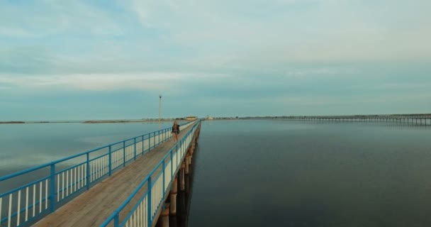 Chica joven caminando en el muelle de madera — Vídeo de stock