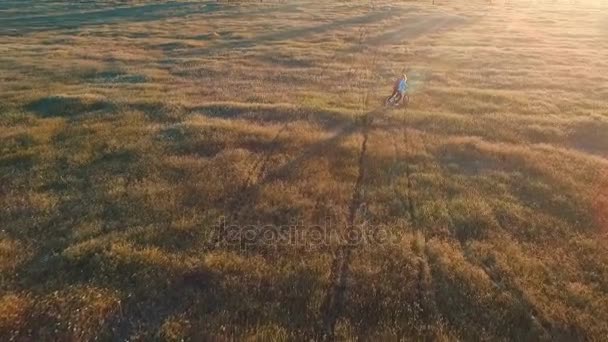 Joven bicicleta ciclista en el área de country sobre el fondo del cielo puesta de sol — Vídeo de stock