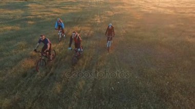 Genç insanlar Bisiklet yeşil ve sarı yaz çayır alan aracılığıyla Bisiklete binme