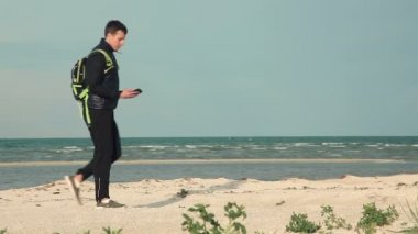 Smartphone deniz kenarında yönlendirme için kullanan genç adam. Gezinti.