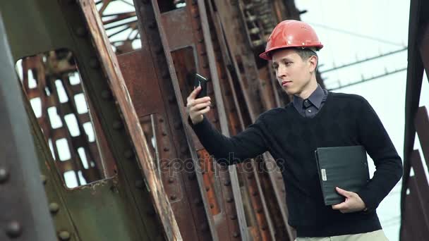 Інженер-будівельник в шоломі робить селфі по телефону — стокове відео
