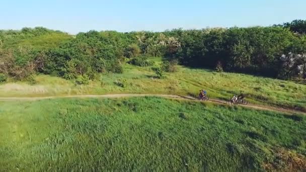 Молоді люди катаються на велосипедах на сільській дорозі — стокове відео