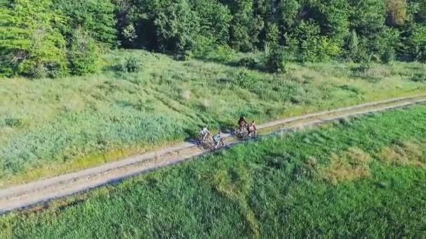 Молоді люди катаються на велосипедах на сільській дорозі — стокове відео