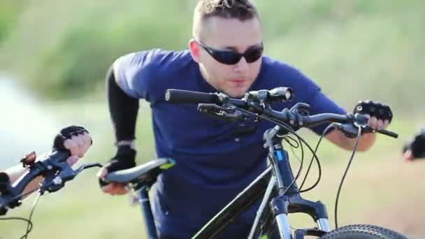 Байкер толкает велосипед вверх по холму — стоковое видео