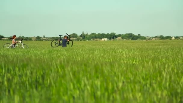 Cyclistes portant des vélos à travers l'herbe haute — Video