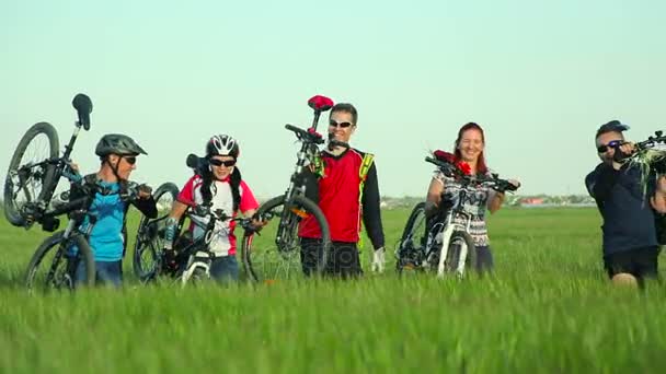 Велогонщики, перевозящие велосипеды по высокой траве — стоковое видео