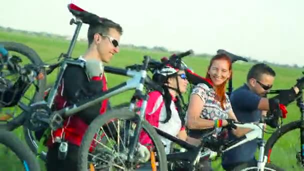 Cyclistes portant des vélos à travers l'herbe haute — Video