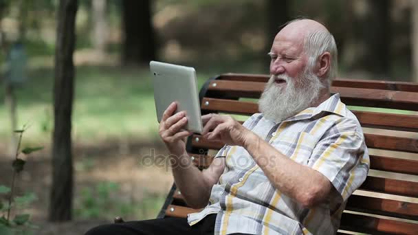 Uomo anziano attraente utilizzando tablet sulla panchina — Video Stock