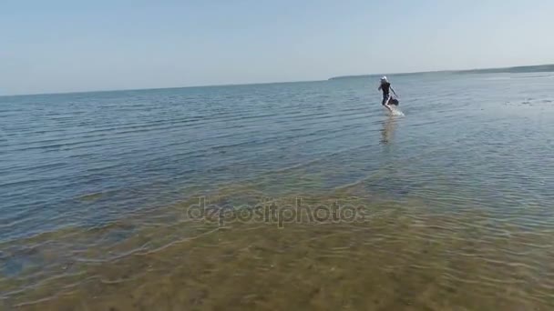 Μια νεαρή και όμορφη κοπέλα τρέχει ξυπόλητος σε όλη την επιφάνεια του νερού. Αργή κίνηση πυροβολισμό από ένα drone. — Αρχείο Βίντεο